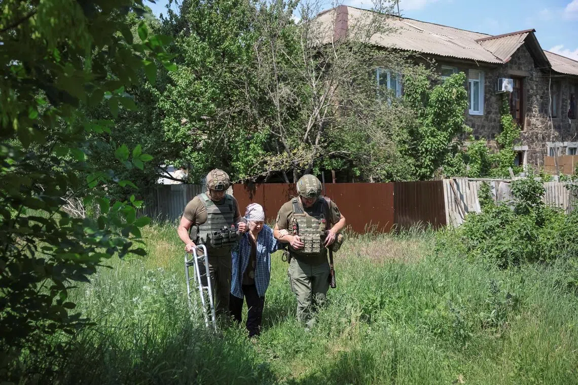 Police officers accompany an elderly woman during evacuation, amid Russia's attack on Ukraine, in the frontline town of Kostyantynivka, Donetsk region, Ukraine June 7, 2025. REUTERS/Anatolii Stepanov