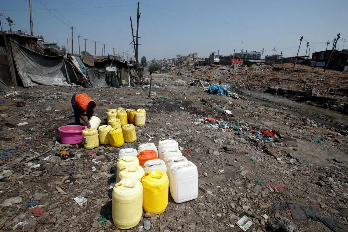FILE PHOTO: A woman cleans plastic jerrycans next to the Nairobi River in Mathare slum in Nairobi, Kenya, July 25, 2024. REUTERS/Monicah Mwangi/File Photo