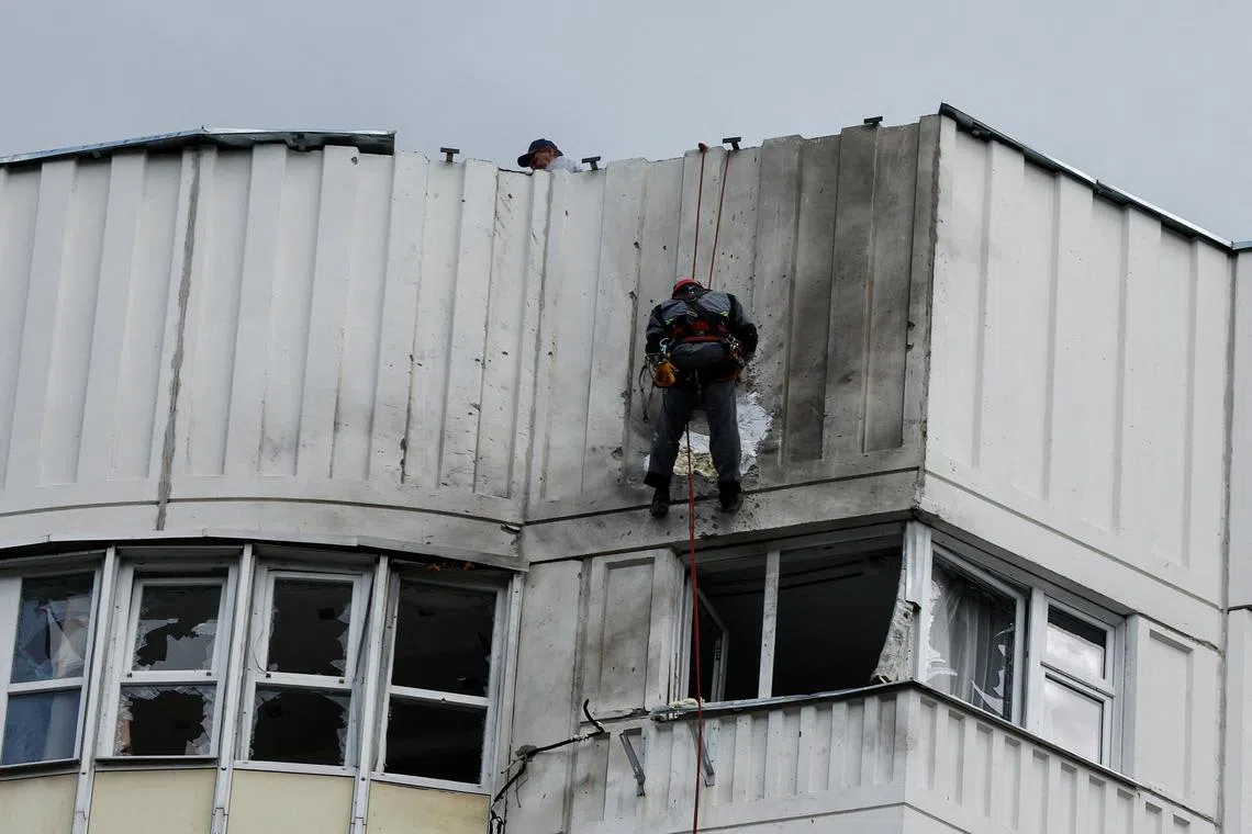 A May 2023 photo shows workers repairing damage to the roof of an apartment block in Moscow, following a reported drone attack. 