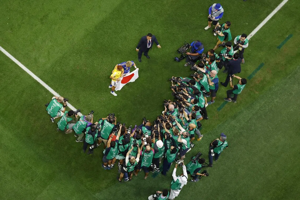 Japan's Ritsu Doan and Yuto Nagatomo pose for photographers as they celebrate after qualifying for the knockout stages