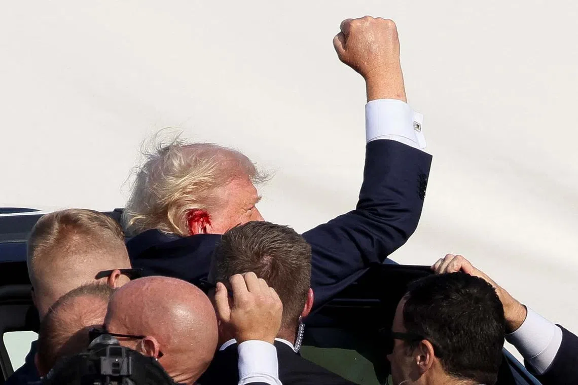 Republican presidential candidate and former U.S. President Donald Trump gestures as he is assisted by security personnel after gunfire rang out during a campaign rally at the Butler Farm Show in Butler, Pennsylvania, U.S., July 13, 2024.