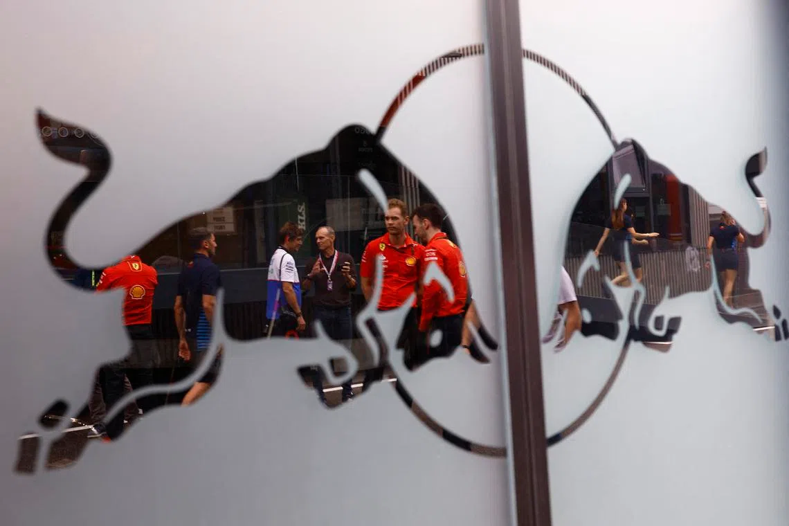 Formula One F1 - Spanish Grand Prix - Circuit de Barcelona-Catalunya, Barcelona, Spain - June 20, 2024 People in the paddock are seen in the reflection of a Red Bull logo ahead of the Spanish Grand Prix REUTERS/Susana Vera
