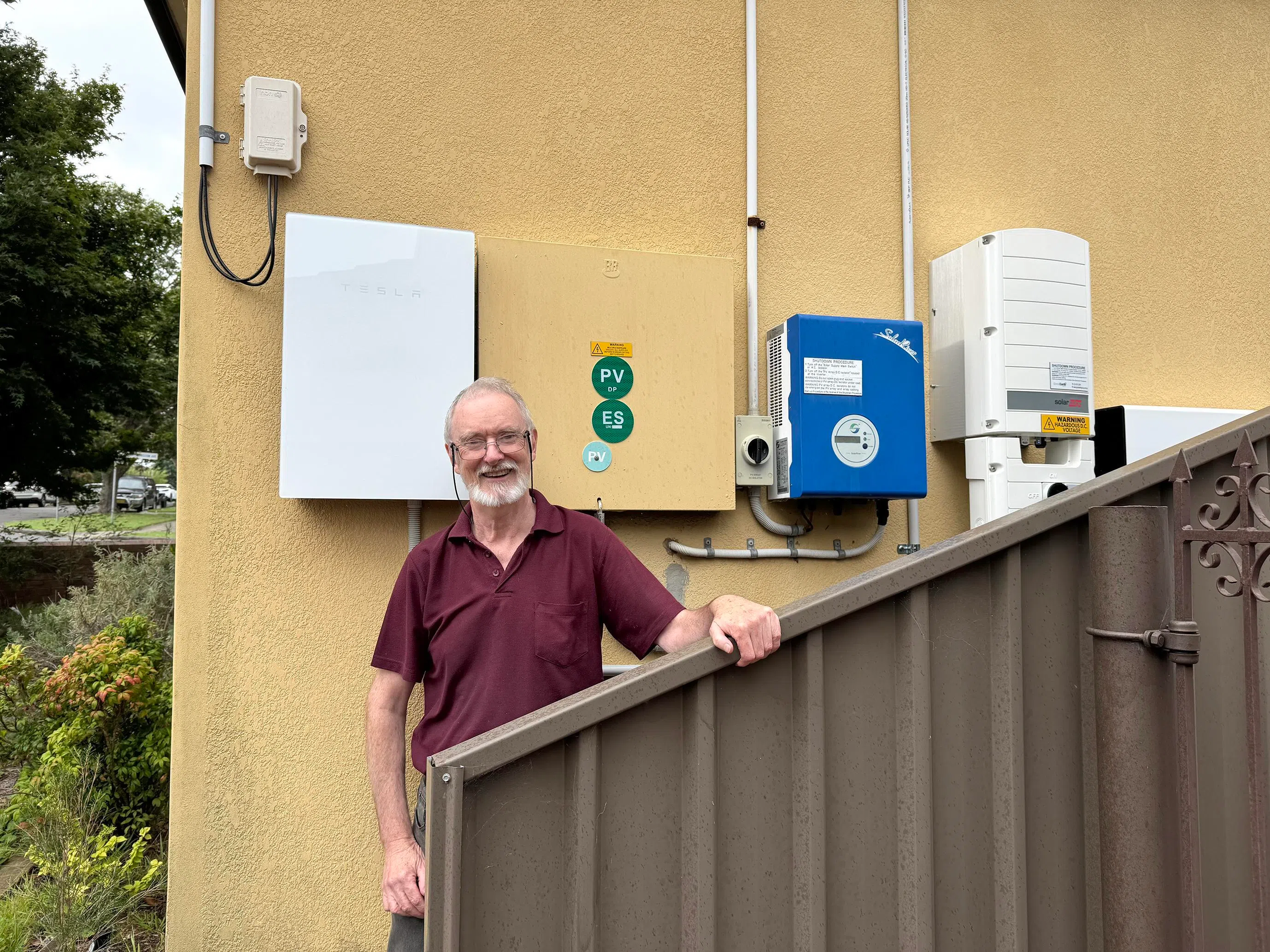 Sydney resident Ken Enderby stands next to his Tesla Powerwall battery at his home. The former teacher estimates he saves more than A$5,000 a year after installing a solar system and battery.