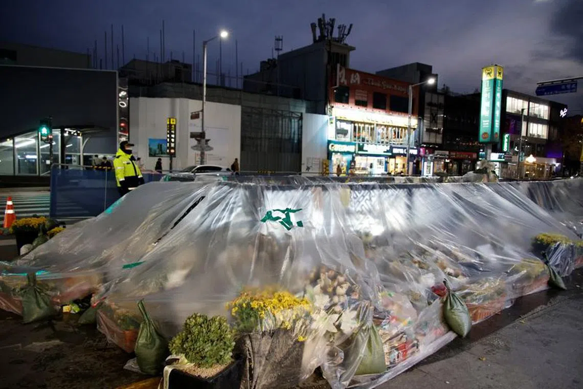A police officer stands guard near floral tributes at the scene of a crowd crush that happened during Halloween festivities, in Seoul, South Korea, November 29, 2022.  REUTERS/Heo Ran/File Photo
