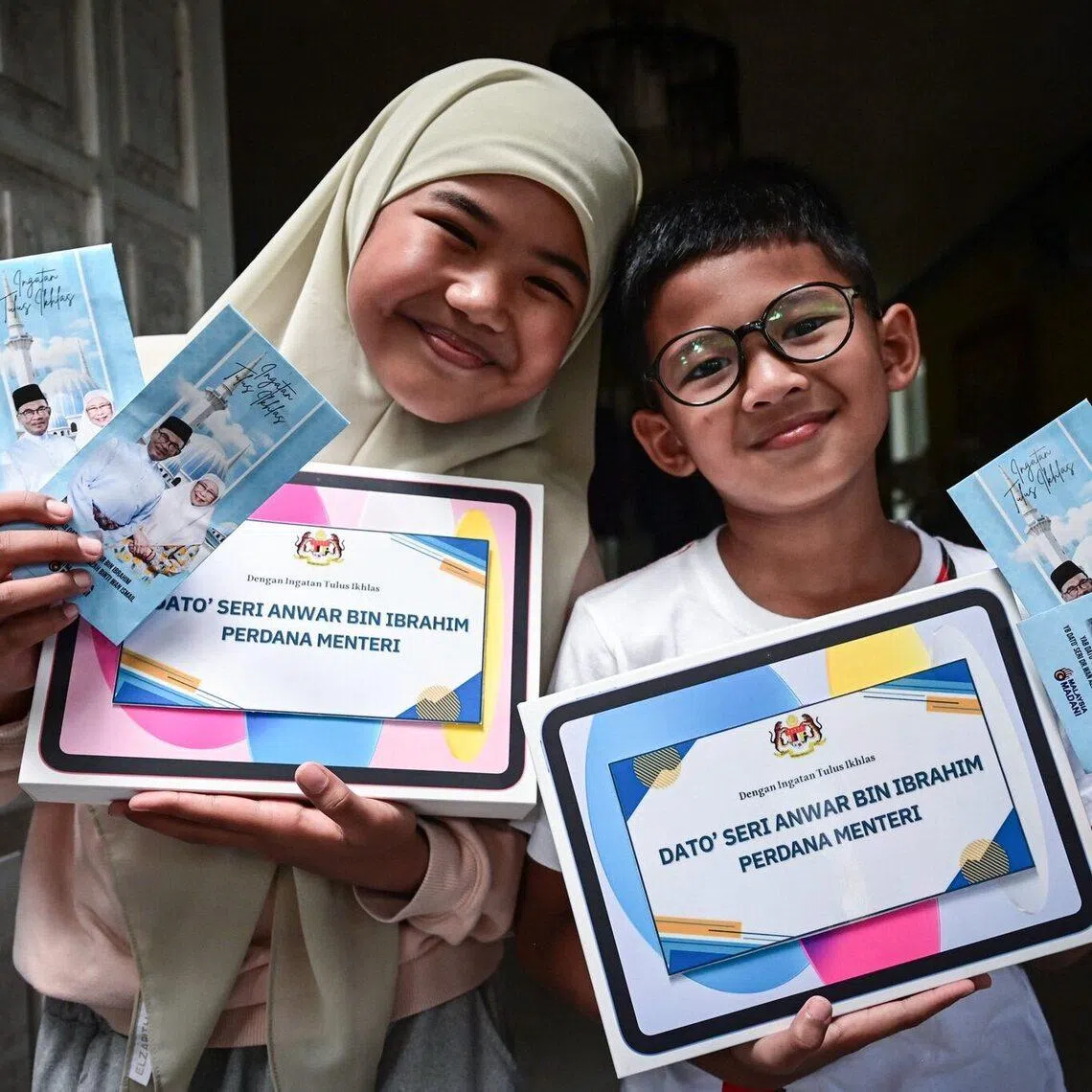 Aesha Khadeeja, 10, and Uwais Al Qorni, 8, pose with gifts sent by Malaysia Prime Minister Anwar Ibrahim. 