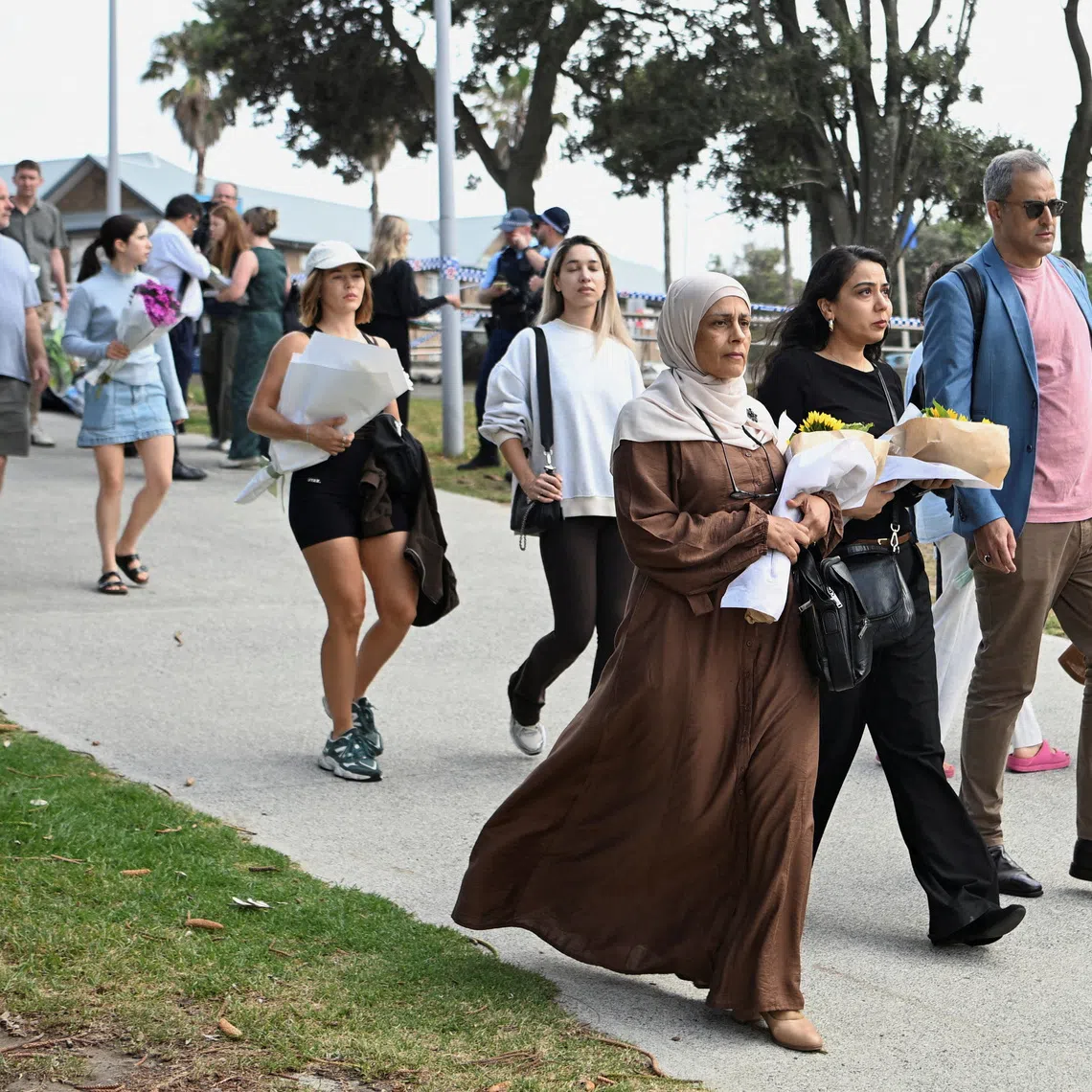 People bring flowers for a makeshift memorial following the attack on a Jewish holiday celebration at Sydney's Bondi Beach, in Sydney, Australia, December 15, 2025. REUTERS/Flavio Brancaleone