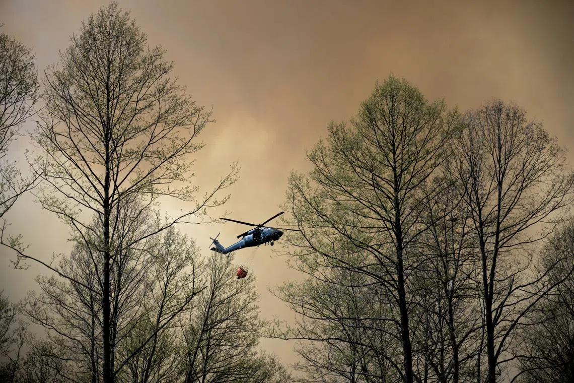 A police helicopter carrying water during efforts to extinguish a forest fire near Jozefow, Poland, on May 6. Hundreds of firefighters battled forest infernos in France, Spain and Portugal on July 5 as temperatures rose again in heatwave-scarred Europe.