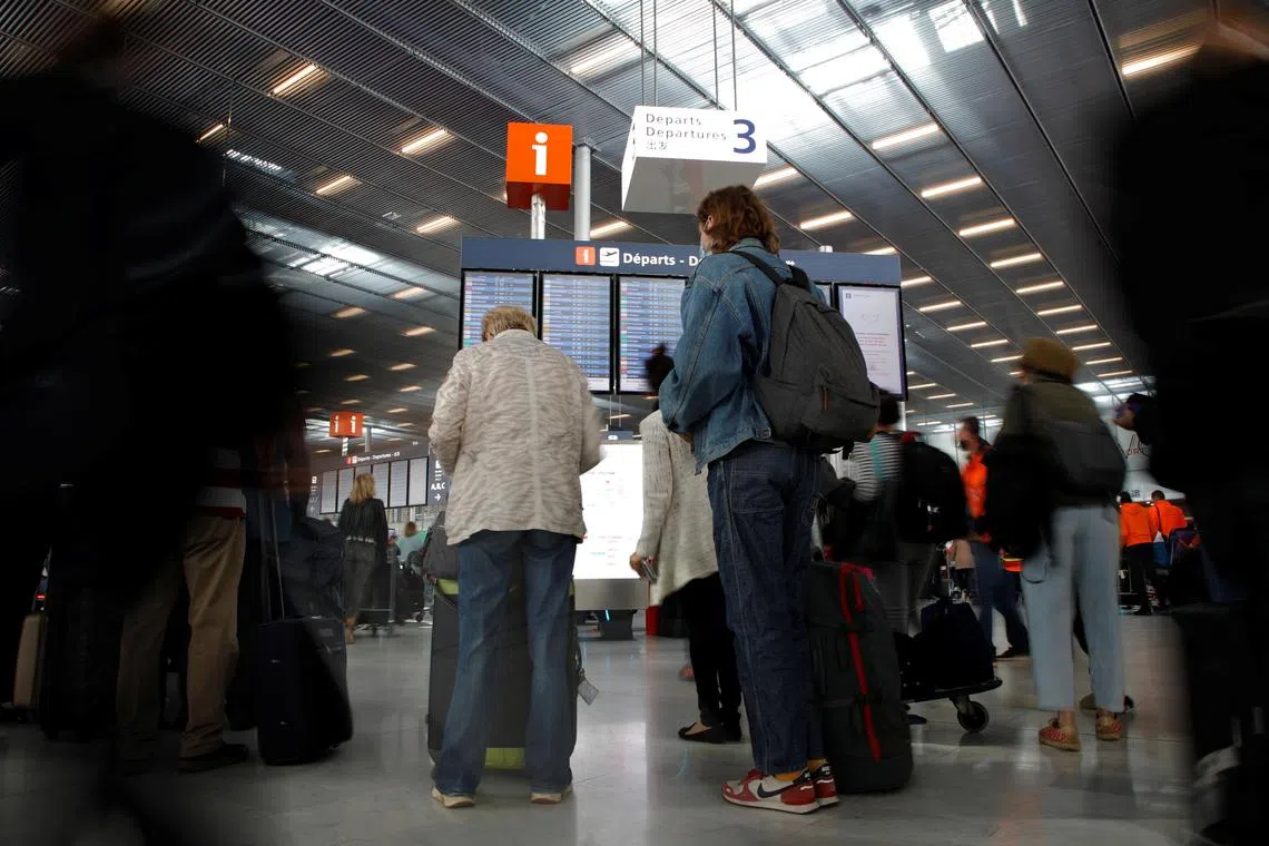FILE PHOTO: Passengers stand in front of a departures board inside the Terminal 3 at Orly Airport, near Paris, France, July 1, 2021. REUTERS/Sarah Meyssonnier/File Photo