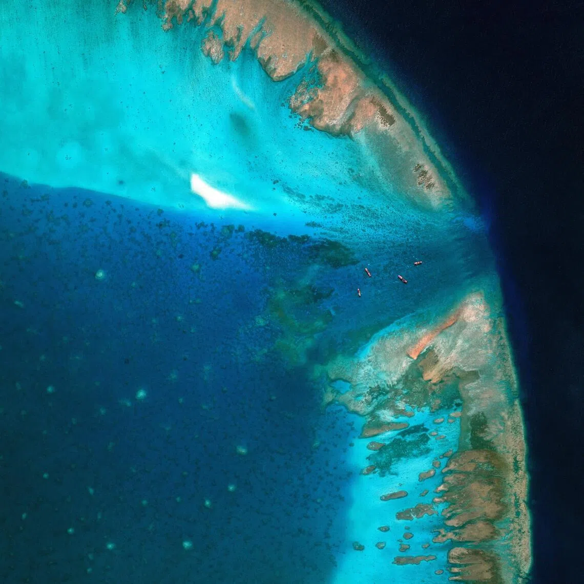 A satellite image of fishing vessels at the entrance, which is blocked by a floating barrier, to the disputed Scarborough Shoal in the South China Sea on April 11, 2026.