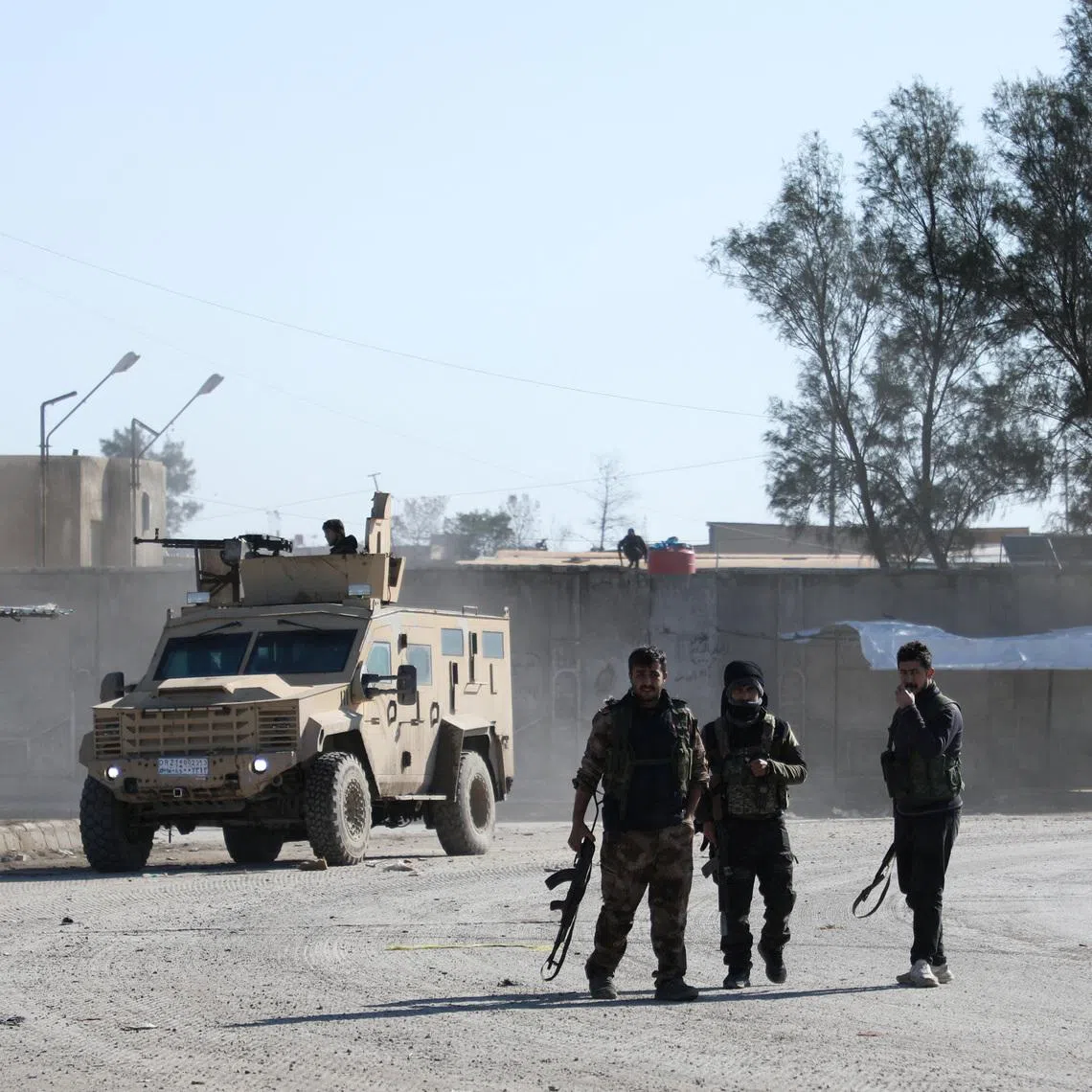Syrian Democratic Forces (SDF) fighters walk near an armored vehicle, following clashes between SDF and Syrian government forces, in Hasakah, Syria, January 20, 2026. REUTERS/Orhan Qereman