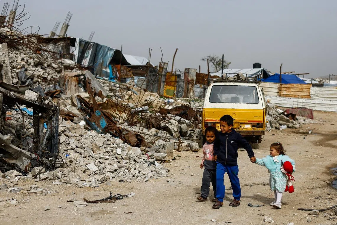 Palestinian children walk past the rubble of residential buildings destroyed during the war, in Gaza City, January 28, 2026. REUTERS/Mahmoud Issa