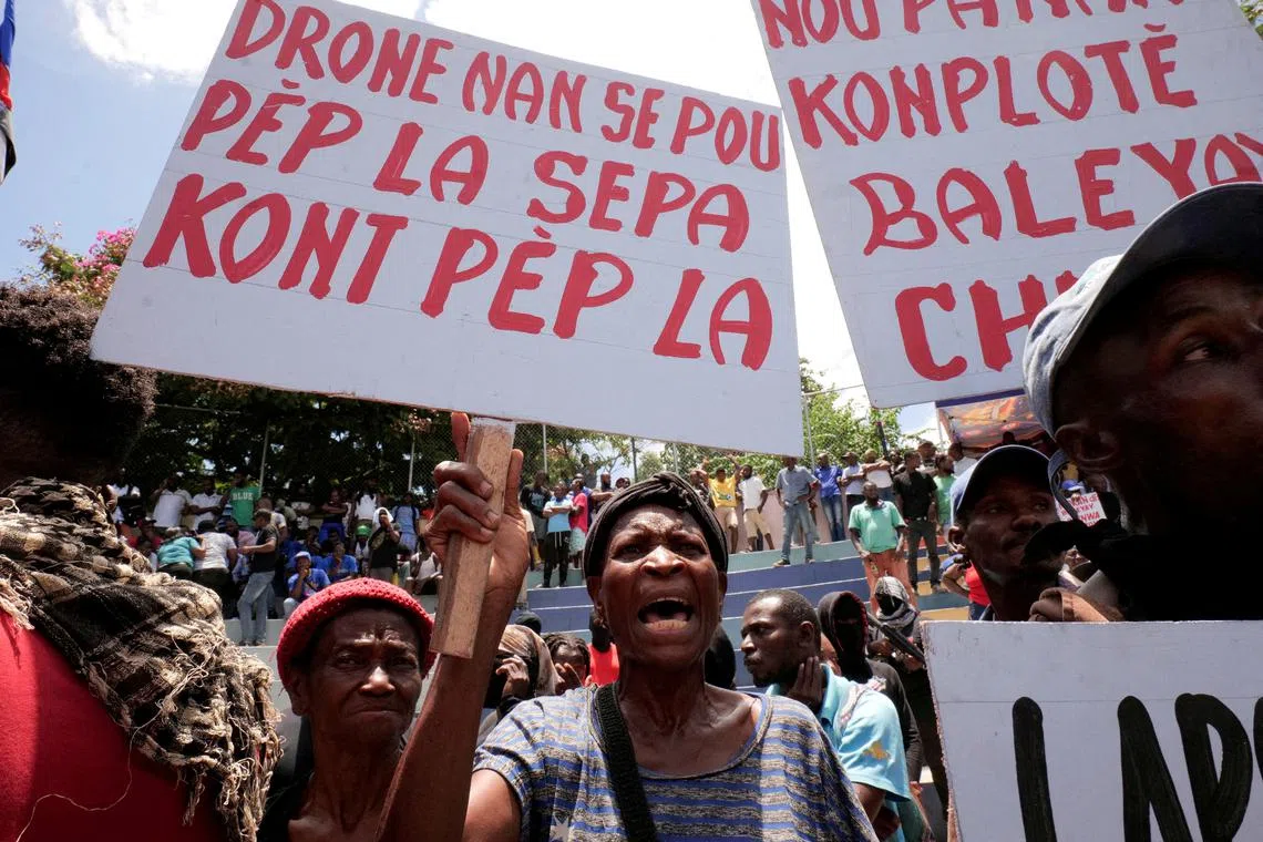 FILE PHOTO: A woman holding a banner that reads in Haitian Creole “Drones are for the people, not against the people”, during a protest against insecurity, in Port-au-Prince, Haiti June 28, 2025. REUTERS/Jean Feguens Regala/File Photo