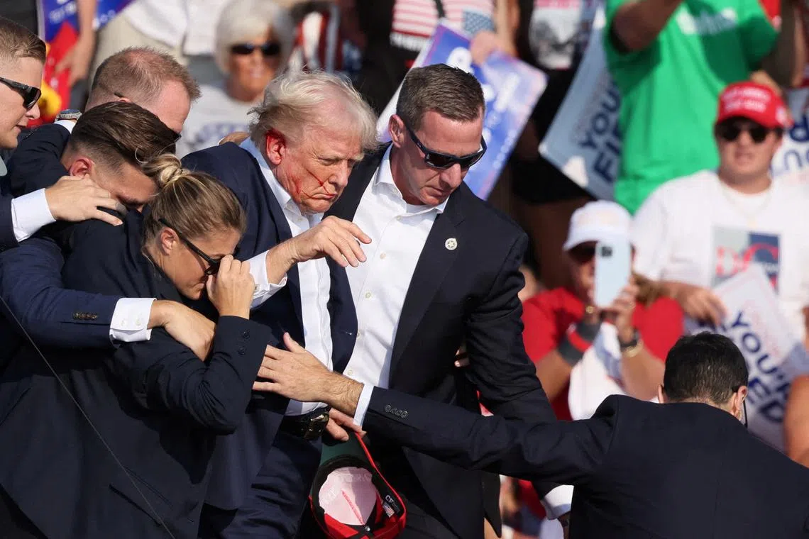 Republican presidential candidate and former U.S. President Donald Trump with his bloodied face is assisted by the Secret Service as multiple shots rang out during a campaign rally at the Butler Farm Show in Butler, Pennsylvania, U.S., July 13, 2024. REUTERS/Brendan McDermid