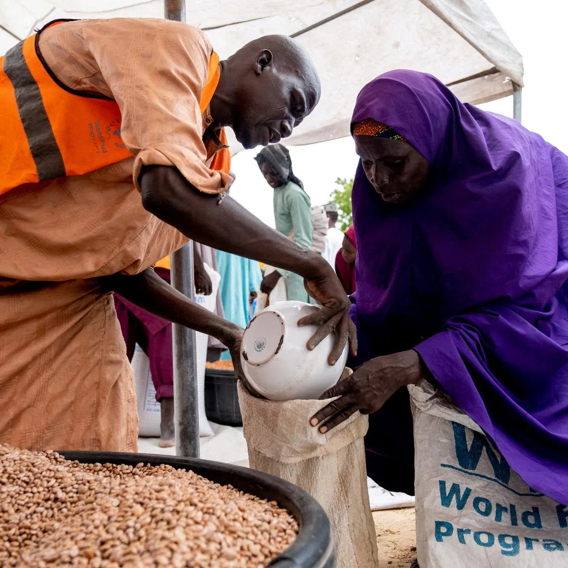 FILE PHOTO: Yaanama Abba, a 45-year-old mother of six children, receives pinto beans distributed by WFP in Mafa LGA, Borno State, Nigeria, July 16, 2025. Damilola Onafuwa, WFP Nigeria Communications Service/Handout via REUTERS/File Photo