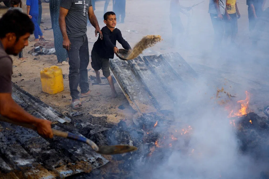 Palestinians put out a fire at the site of an Israeli strike on an area designated for displaced people, in Rafah, in the southern Gaza Strip, May 27, 2024. REUTERS/Mohammed Salem