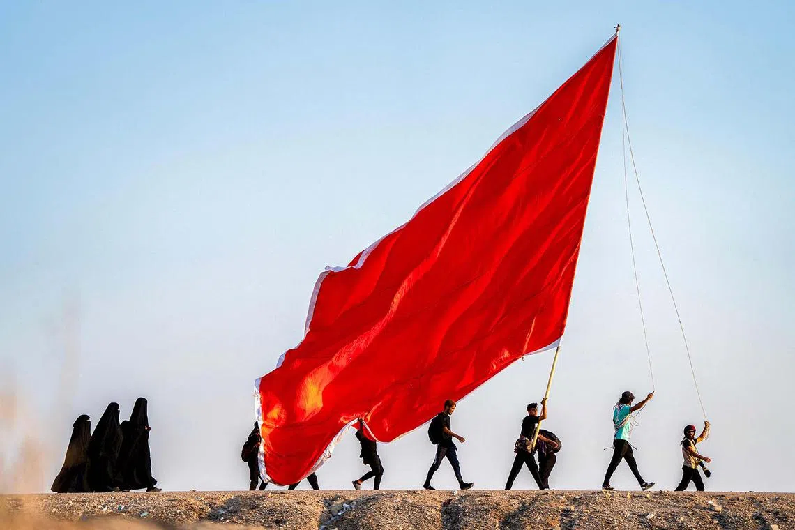 Shiite Muslim pilgrims marching with banners towards the shrine city of Karbala ahead of the Arbaeen commemorations that mark the end of the 40-day mourning period for the seventh century killing of the Prophet Mohamed's grandson Imam Hussein ibn Ali, in the city of Nasiriyah in Iraq on Aug 14, 2024. 