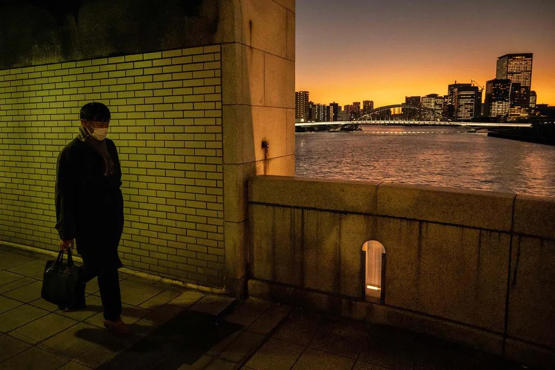 A man walks on a bridge at sunset in Tokyo on December 20, 2022. (Photo by Yuichi YAMAZAKI / AFP)