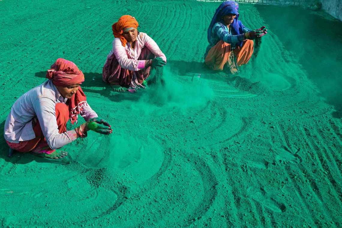 Workers preparing to dry 'Gulal' or coloured powder popularly used during the Hindu spring festival of Holi, before the packing process at a workshop in Mathura on Feb 25, 2023. 