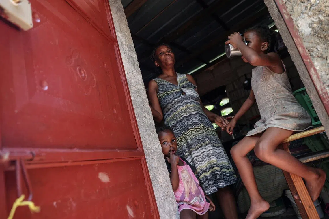 FILE PHOTO: Rita Losandieu, 53, stands in front of her house with her two granddaughters Solius, 4, and Alisha, 6, in the Monoville area of the Juvenat neighbourhood in Port-au-Prince, Haiti, May 7, 2024. REUTERS/Ricardo Arduengo/File Photo