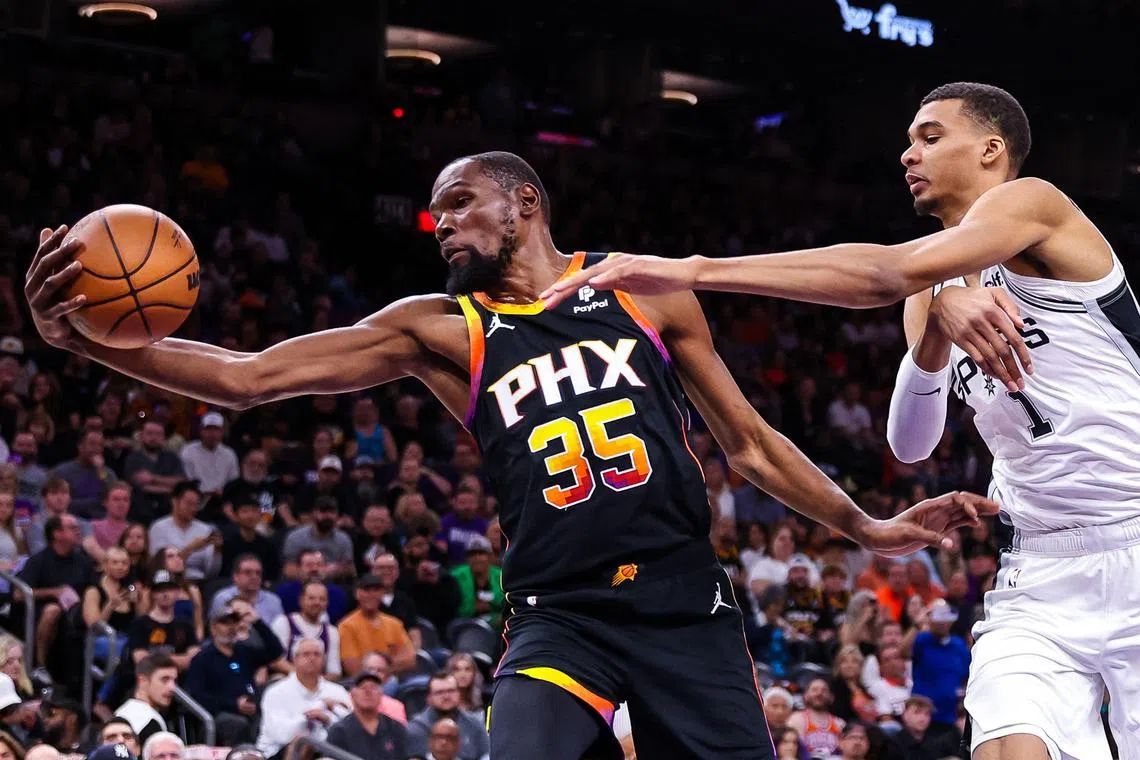 Kevin Durant of the Phoenix Suns going after a rebound alongside San Antonio's Victor Wembanyama in their match at the Footprint Center on Tuesday.