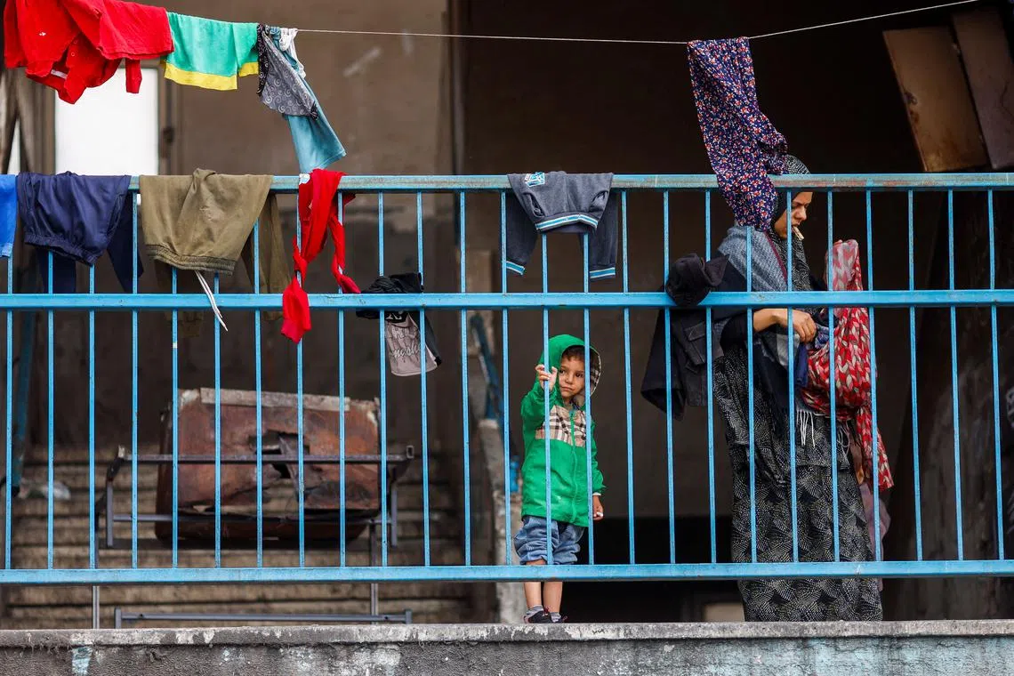Palestinians stand behind the railings at a nearly deserted school used as a shelter by displaced people who fled Rafah after Israeli forces launched a ground and air operation in the eastern part of the southern Gaza City, amid the ongoing conflict between Israel and Hamas, in Rafah, in the southern Gaza Strip May 13, 2024. REUTERS/Mohammed Salem