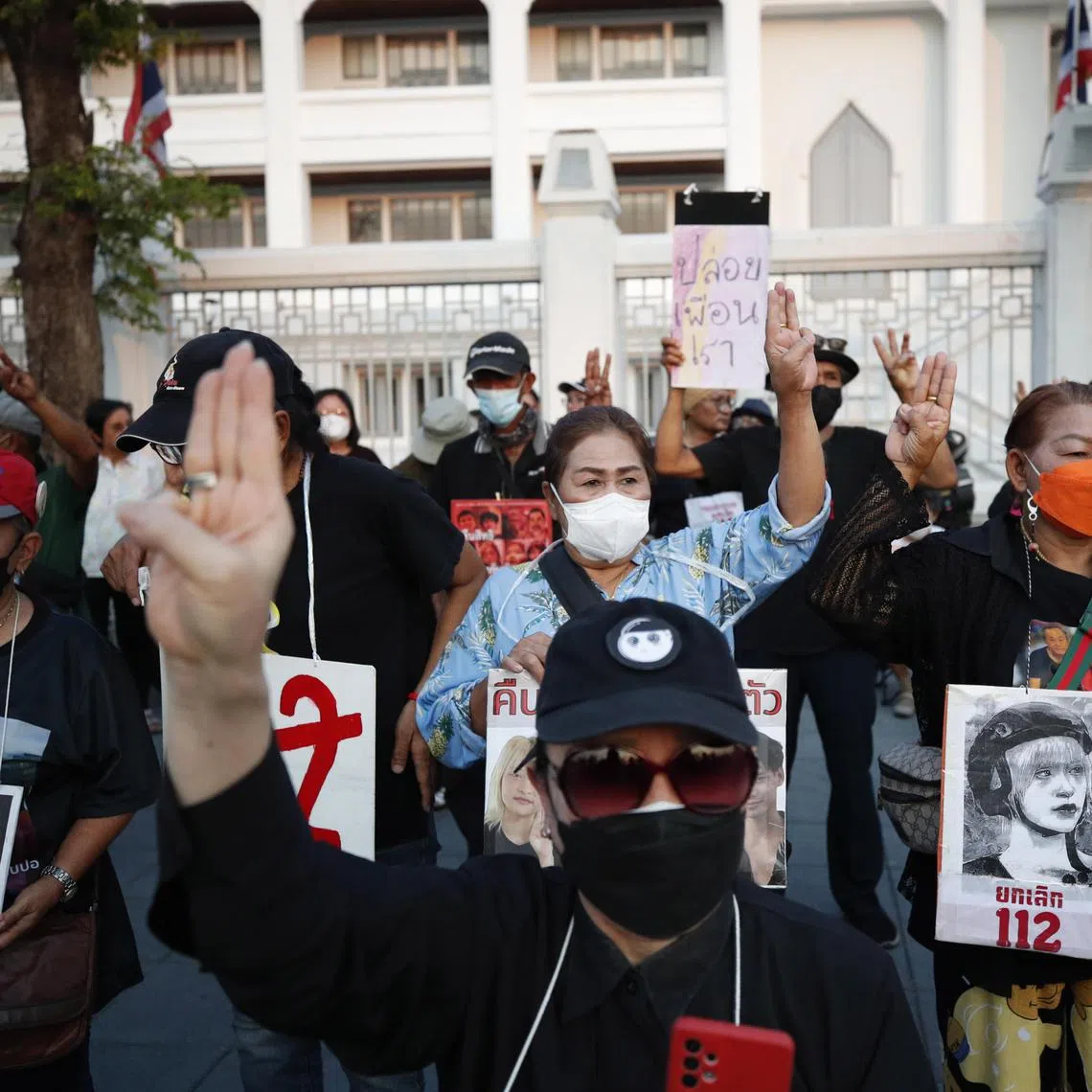 epa10488218 Protesters flash the defiant three-finger salute and hold banners calling for the abolition of the section 112 criminal code (lese-majeste law) and free political prisoners during a demonstration to support the hunger strike of two activists outside the Supreme Court in Bangkok, Thailand, 24 February 2023. Two young activists accused of lese-majeste, Tantawan Tuatulanon and Orawan Phupong, began a hunger strike on 18 January 2023 calling to reform the justice system, abolish the lese-majeste law, and release political prisoners detained on royal defamation charges.  EPA-EFE/RUNGROJ YONGRIT