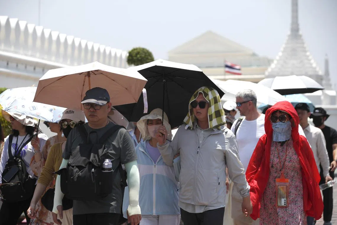 Tourists shield themselves from the sun during hot weather outside the Grand Palace in Bangkok, on April 29.