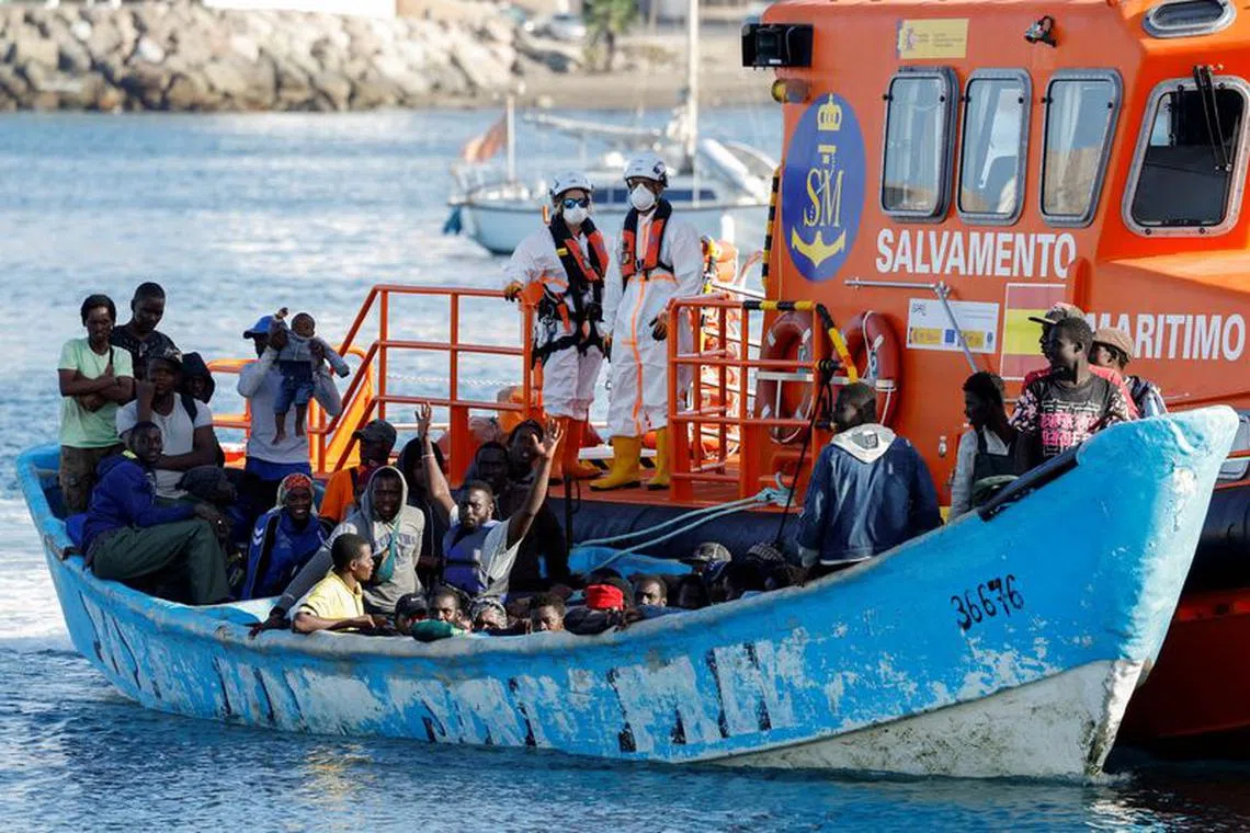 FILE PHOTO: A group of migrants in a wooden boat are towed by a Spanish coast guard vessel to the port of Arguineguin, in the island of Gran Canaria, Spain, October 12, 2023. REUTERS/Borja Suarez/File Photo