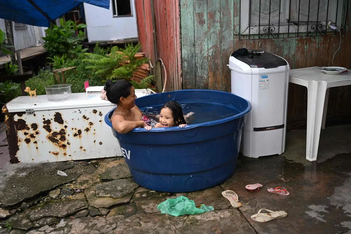 A woman and her daughter take a bath in an improvised pool at Vila da Barca, a neighbourhood of stilt houses on the banks of the Guama River in Belem, Brazil, on Nov 5.