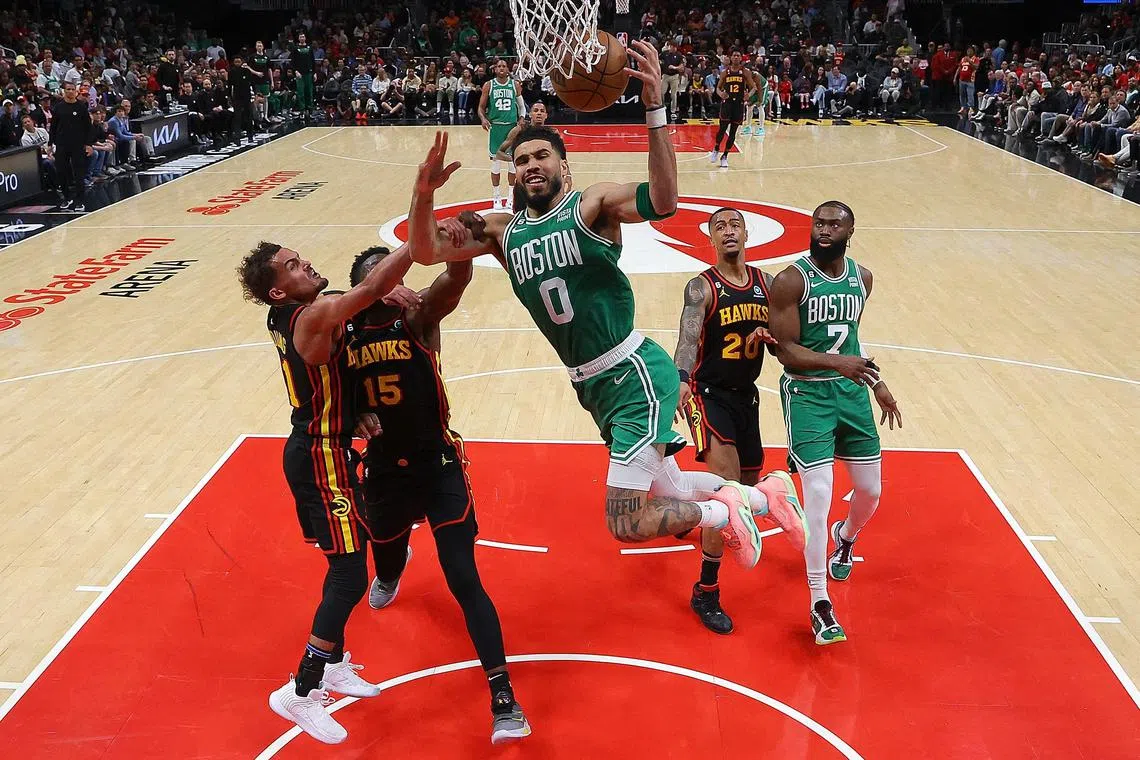 Jayson Tatum of the Boston Celtics drawing a foul as he drives against Clint Capela and Trae Young of the Atlanta Hawks during the fourth quarter of game four of the Eastern Conference play-offs.