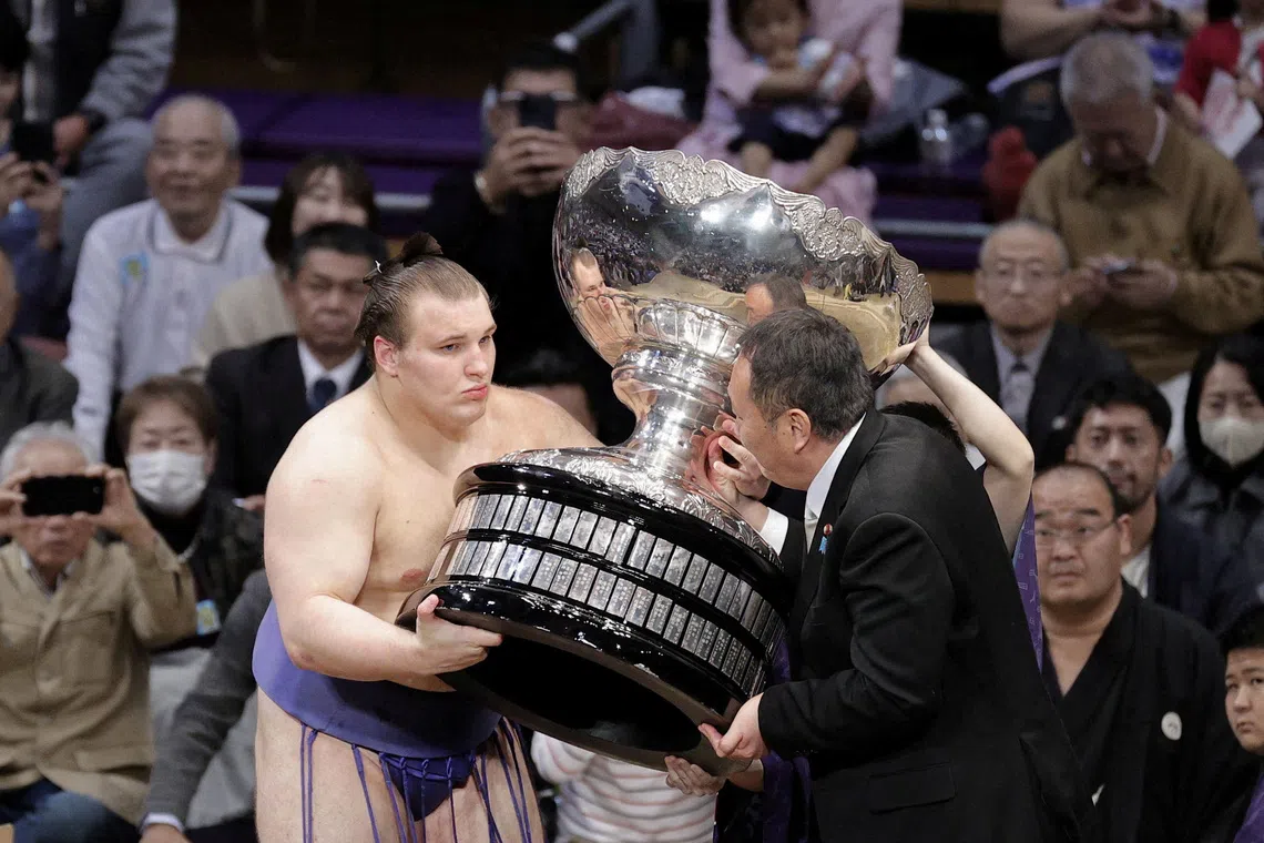 21-year-old Ukrainian sumo wrestler sekiwake Aonishiki, his real name Danylo Yavhusishyn, receives the Prime Minister's Cup from Takahiro Inoue, an advisor to Prime Minister Sanae Takaichi, after becoming the first from his nation to win a tournament of traditional Japanese sport, on the final day of the 15-day Kyushu Grand Sumo Tournament, at Fukuoka Kokusai Center in Fukuoka, southwestern Japan, November 23, 2025.   Kyodo/via REUTERS