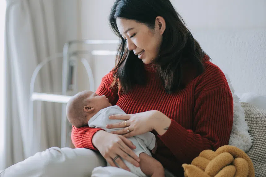 Young asian woman carrying newborn baby