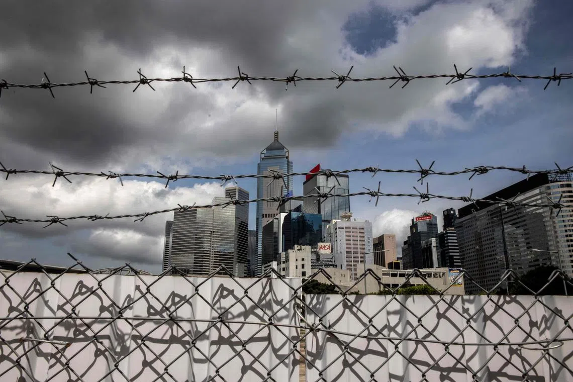 This photo taken on June 29, 2023 shows barbed wire fencing with the Wan Chai district in the background in Hong Kong. After massive and at times violent pro-democracy protests in 2019, and Beijing's subsequently imposed national security law, Hong Kong has used the sedition offence -- created under British colonial rule -- to charge residents for the first time in over 50 years. (Photo by Isaac LAWRENCE / AFP) / TO GO WITH HongKong-China-politics-law-sedition, FOCUS by Xinqi SU