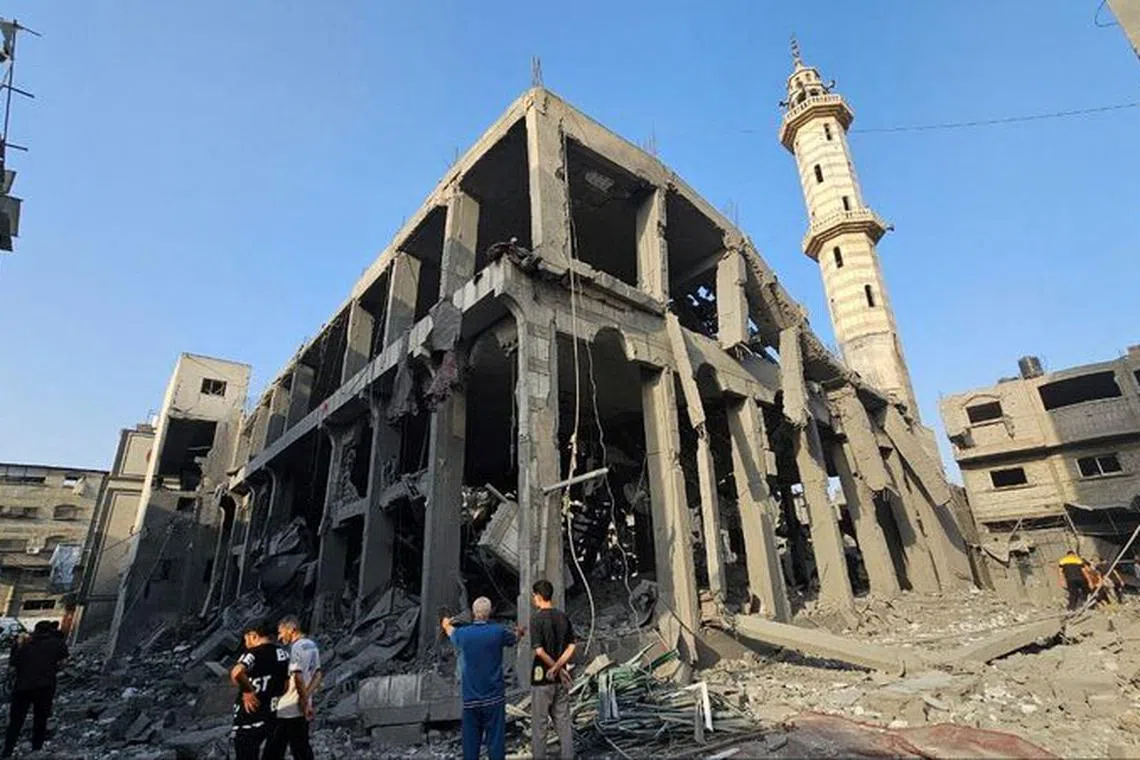 Palestinians gather around the remains of a mosque destroyed in Israeli strikes, as the conflict between Israel and Palestinian Islamist group Hamas continues, in the northern Gaza Strip October 22, 2023. REUTERS/Anas al-Shareef