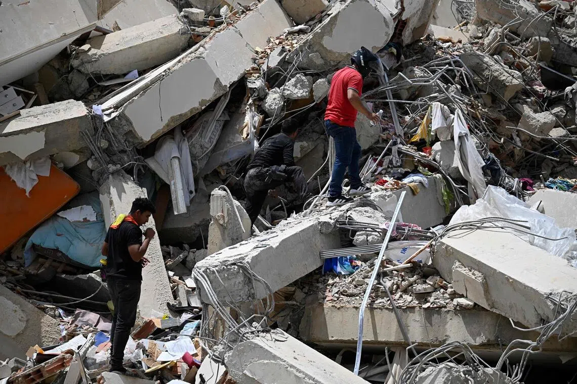 Volunteers search for possible victims in a collapsed building following twin earthquakes in Caraballeda, Caracas, on June 25.
