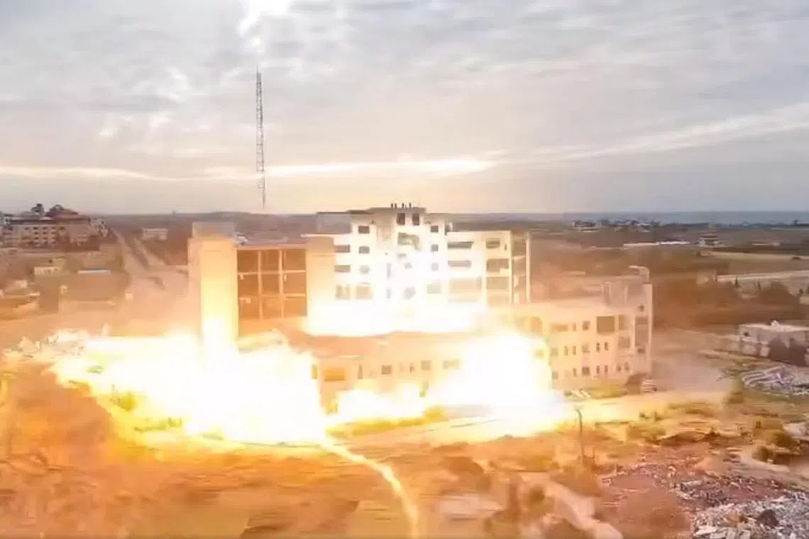 A screengrab of a video showing the main building of Israa University being blown up in what appears to be a controlled demolition.