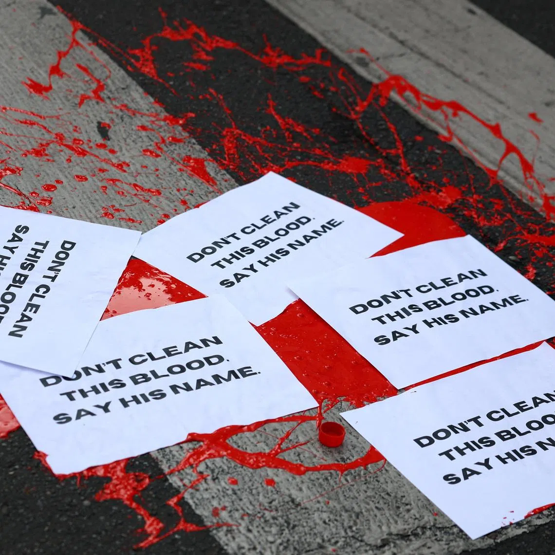 Papers reading \"Don't clean this blood, say his name\" lie on a street on top of red paint, during a protest following the death of Abderrahim Fakir, as police restrained him during an attempted detention in a street in Bologna, in Milan, Italy, July 21, 2026. REUTERS/Claudia Greco