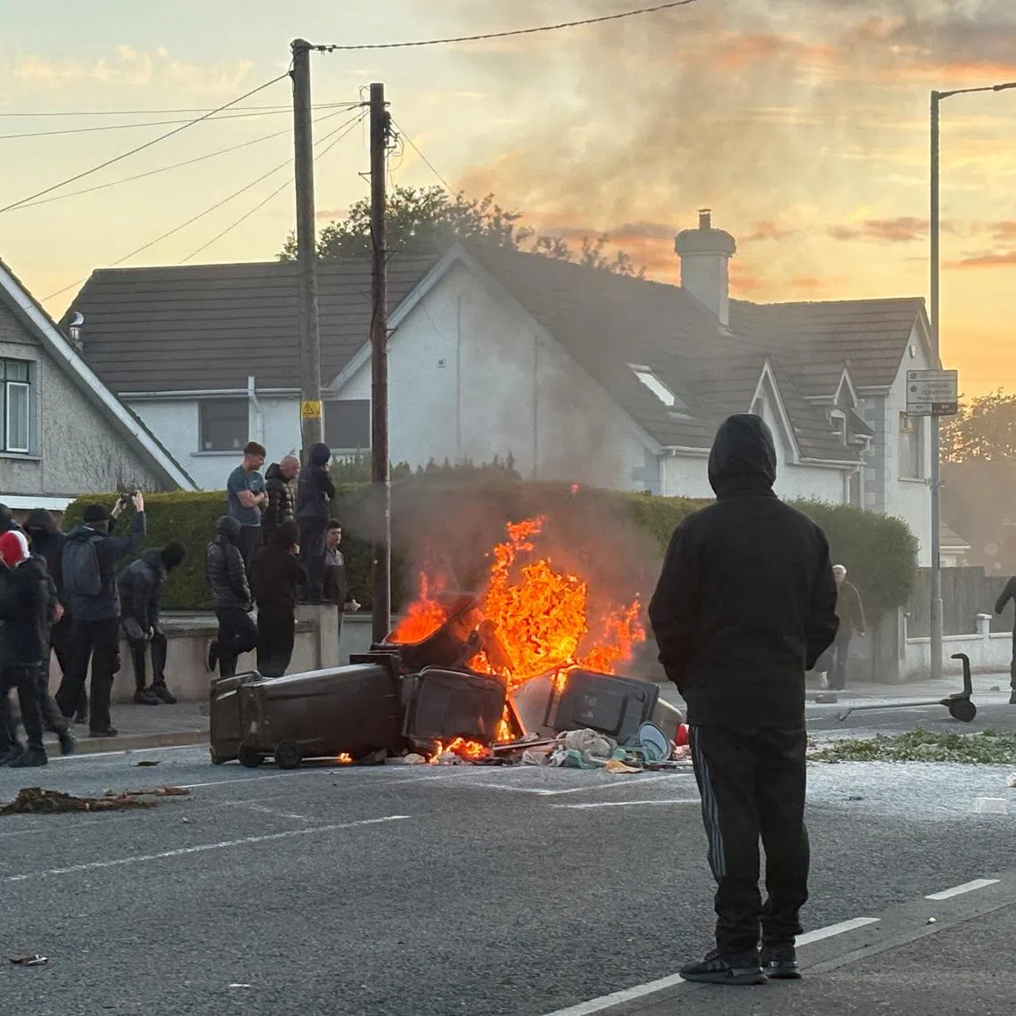 A fire burns in bins as anti-immigrant protesters clash with police at Antrim road, following a knife attack on June 8, which left a man seriously injured and prompted police to declare a critical incident, in Belfast, Northern Ireland, June 10, 2026. Picture taken with a phone. REUTERS/Isabel Infantes
