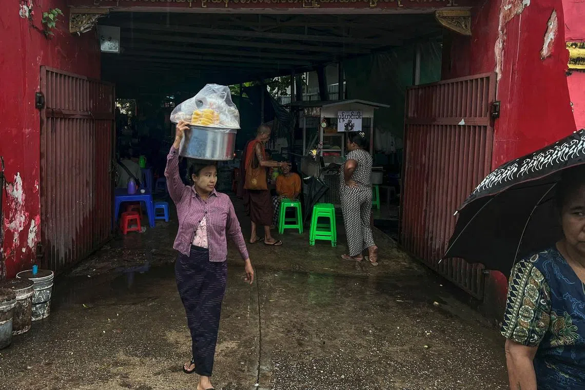 A street food vendor carries a pot on her head as it rains in Yangon on June 18. A 'squatter ward' in the city has reported a cholera outbreak with nine people testing positive for the illness.