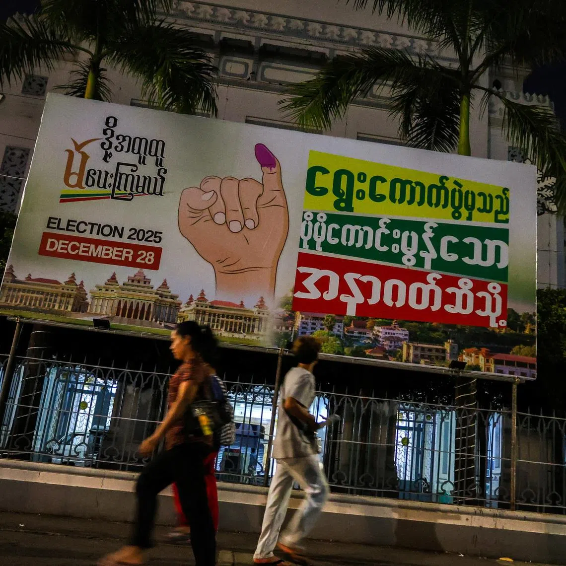 People walk past an election banner ahead of a general election in Thingangyun Township, Yangon, Myanmar, on Dec 27, 2025.
