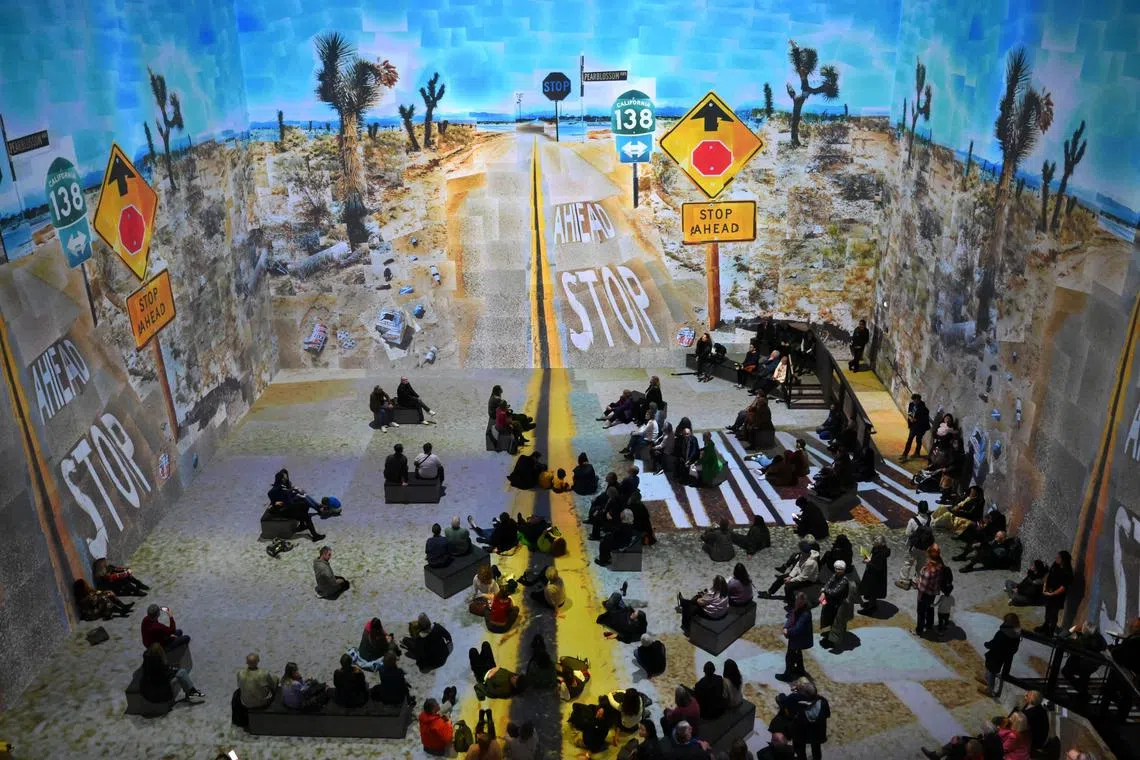 Visitors attend the 'David Hockney: Bigger & Closer (not smaller & further away)’ immersive exhibition at the Lightroom gallery in London on Feb 22, 2023.  David Hockney's first immersive show opened to the public in London Wednesday offering a hypnotic, multi-sensory journey through the artist's decades-long career, from sun-drenched California swimming pools to the Normandy countryside. "The world is a very very beautiful if you look at it. Most people don't look," says Hockney in his commentary which runs through the show, along with archive recordings. 