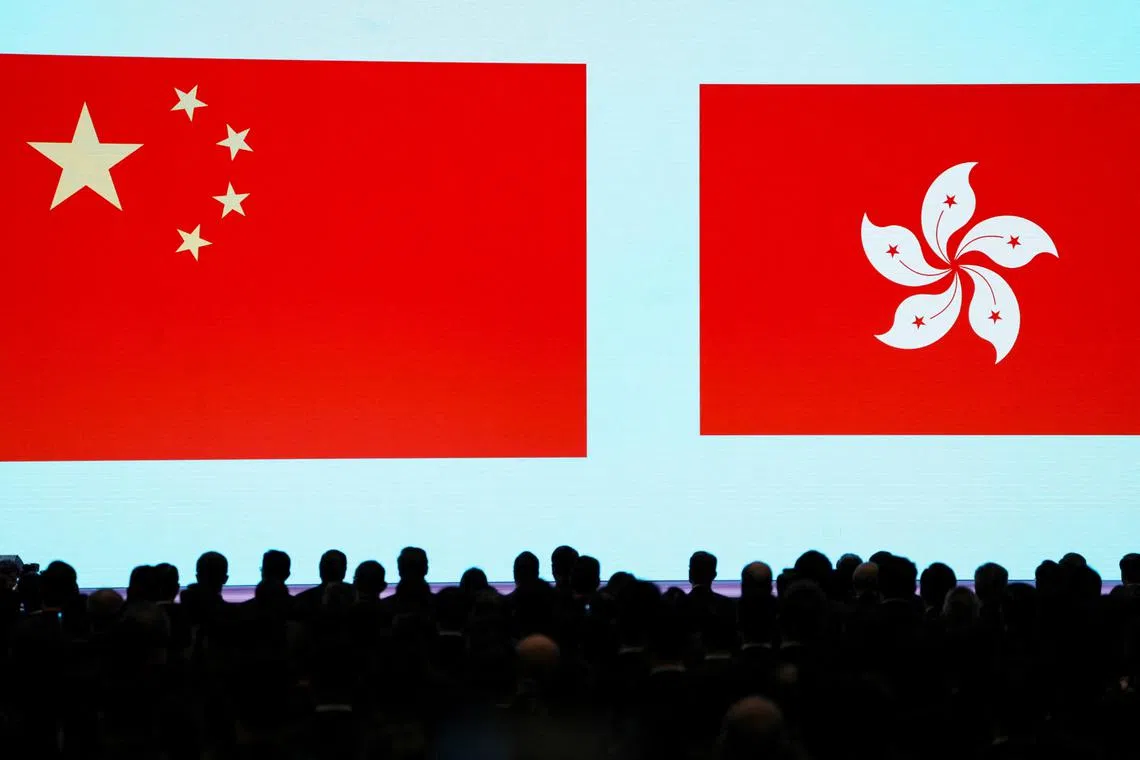 People stand in front of a screen showing the Chinese and the Hong Kong flags during the National Security Education Day opening ceremony in Hong Kong, China April 15, 2024. REUTERS/Lam Yik
