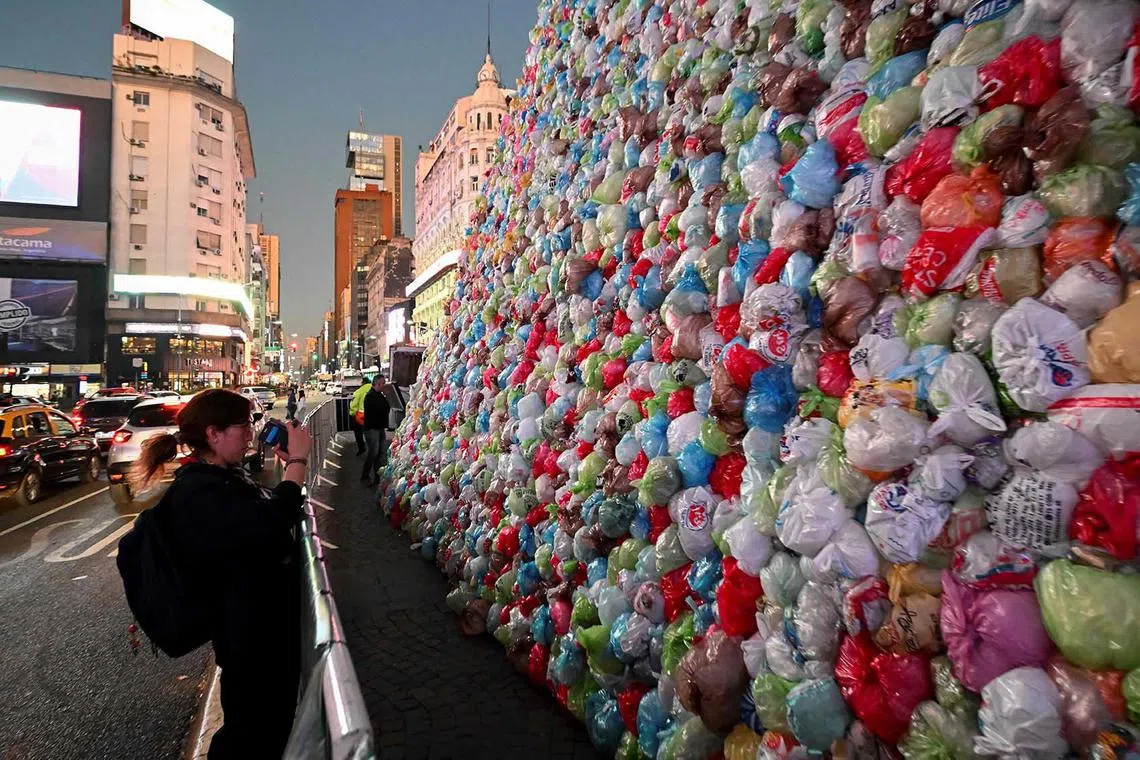 A woman takes pictures of the Obelisk covered with plastic bags as part of an artistic intervention on the eve of World Recycling Day in Buenos Aires on May 16.
