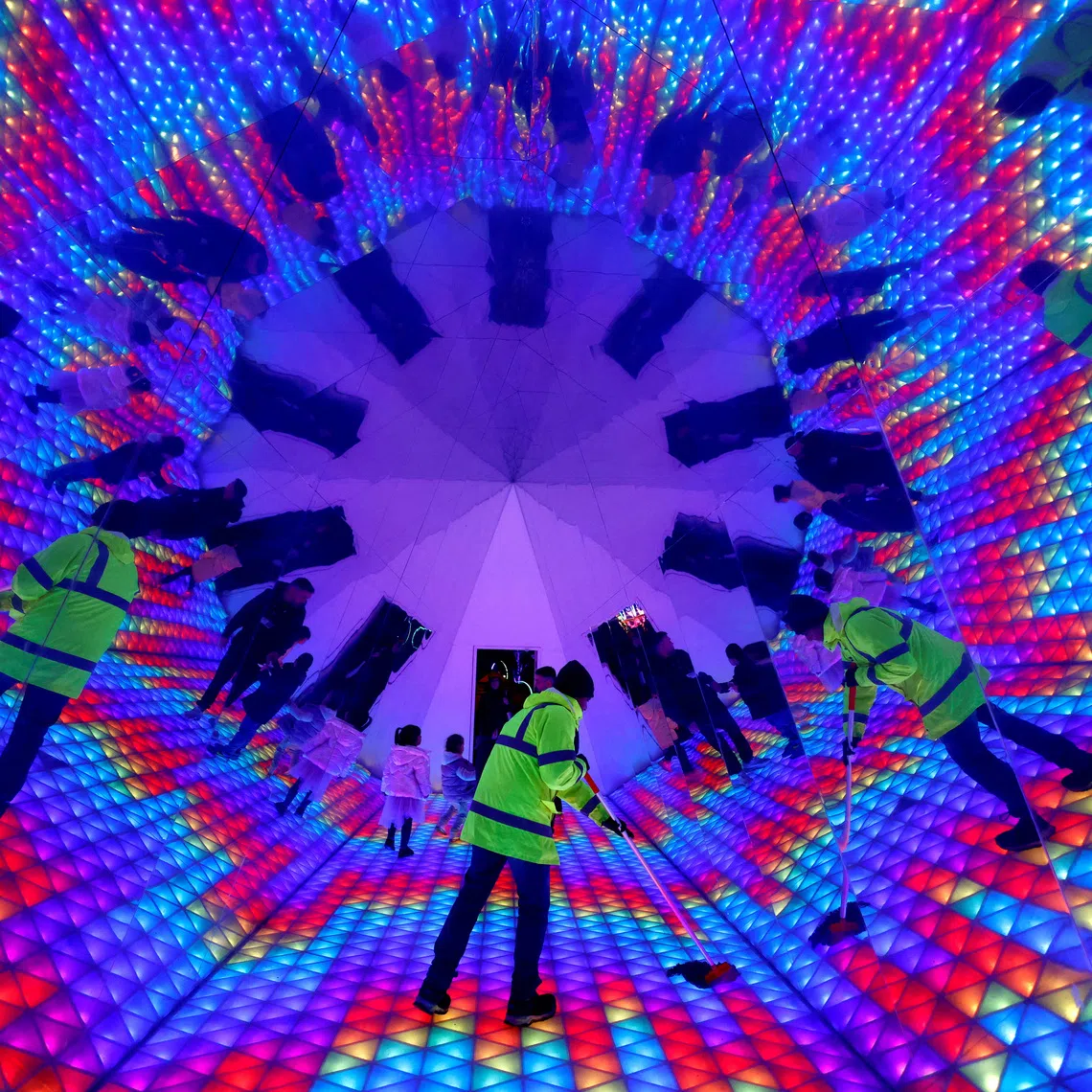 A worker mopping the floor inside a kaleidoscope tunnel at a winter lights Christmas installation, in Dublin, Ireland, on Dec 3, 2025. 