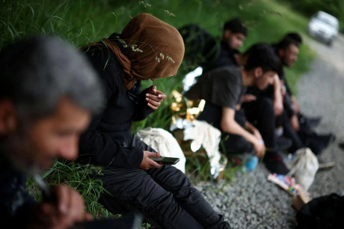 FILE PHOTO: Migrants sit in the forest, after crossing the Belarusian-Polish border, near Grudki, Poland, June 4, 2024. REUTERS/Kacper Pempel/File Photo