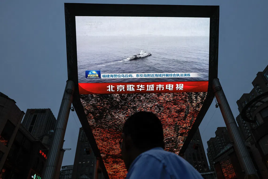 A person looks at a screen showing news footage of military drills conducted in areas around the island of Taiwan by the Eastern Theatre Command of the Chinese People's Liberation Army (PLA), in Beijing, China May 23, 2024. REUTERS/Tingshu Wang