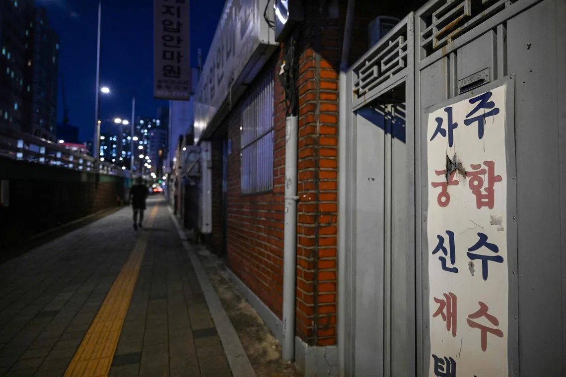 This photo taken on July 29, 2026 shows a sign advertising fortune telling services outside the apartment where blind fortune-teller Song Oh-soon sees clients in the Mia-ri fortune-telling village in Seoul. Clients have drifted away from Song Oh-soon's fortune-telling village on the edge of Seoul, preferring online AI-powered divination to the centuries-old prophesying tradition still practised there. (Photo by GREG BAKER / AFP) / To go with 'SKOREA-LIFESTYLE-CULTURE-TECHNOLOGY-DISABILITY,FOCUS' by Jihye SHIN