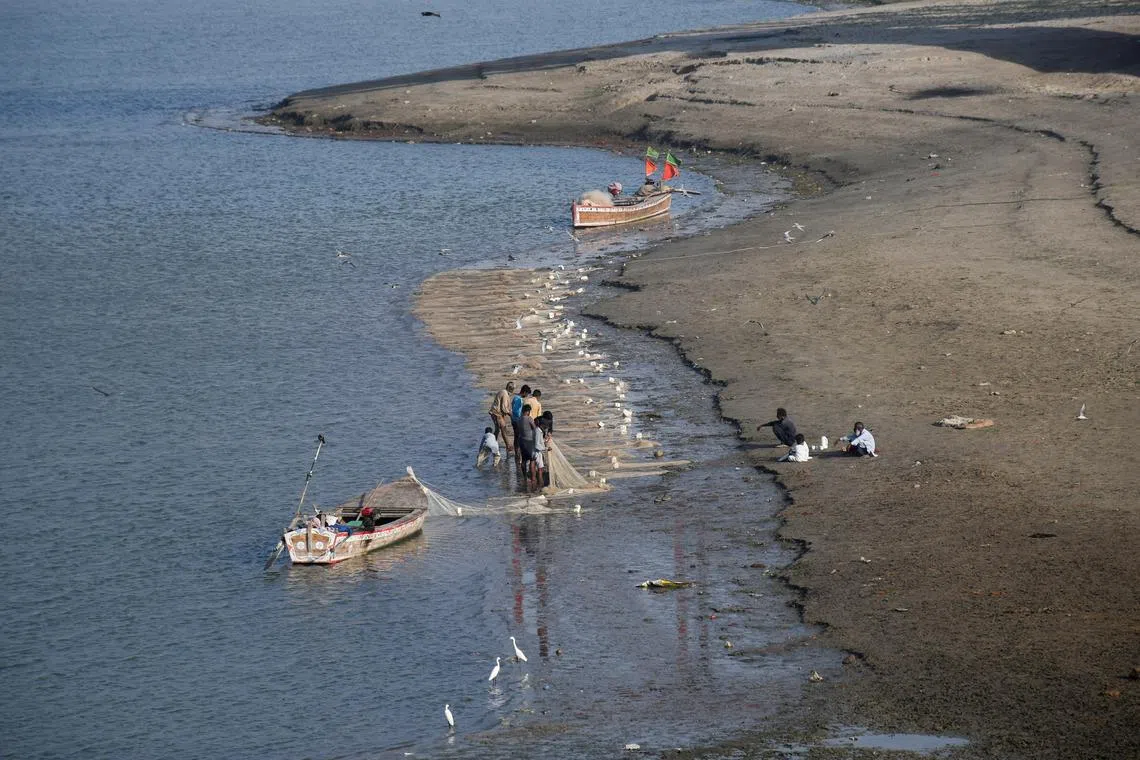 FILE PHOTO: Fishermen clear a fishing net in the water on the partially dried up riverbed of the Indus River in Hyderabad, Pakistan April 25, 2025. REUTERS/Yasir Rajput/File Photo