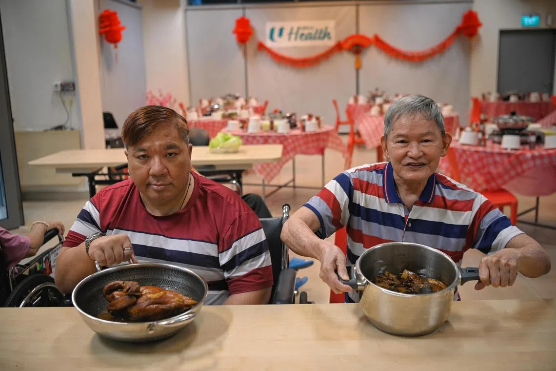 Francis Lim (left), 53, an ex-Hyatt hotel chef and Tan Lam Huat, 74, display their dishes of stewed chicken and pigs trotters, ahead of their reunion dinner with the other residents of the NTUC Health Nursing Home in Jurong West on January 19, 2023.