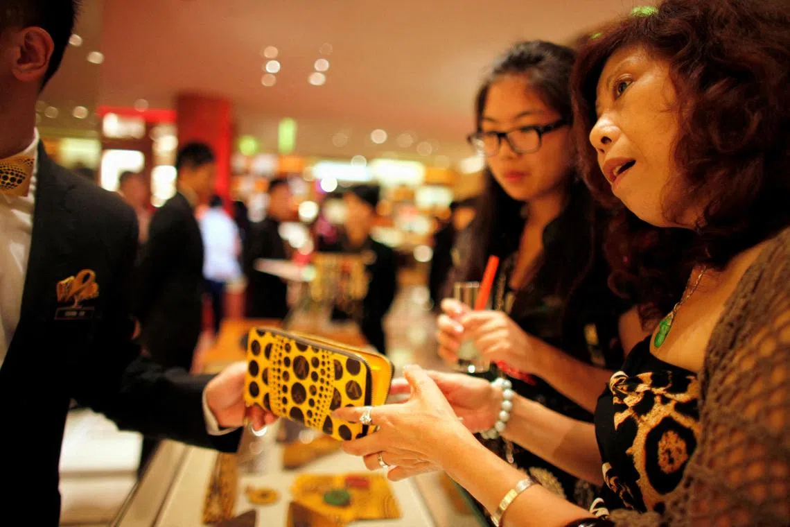 FILE PHOTO: A woman shops in a Louis Vuitton store during Vogue's 4th Fashion's Night Out in downtown Shanghai September 7, 2012. Louis Vuitton is courting China's wealthy with one-of-a-kind shoes and bags it is branding as unique works of art to reclaim its exclusive cachet in the luxury market.  REUTERS/ Carlos Barria//File Photo
